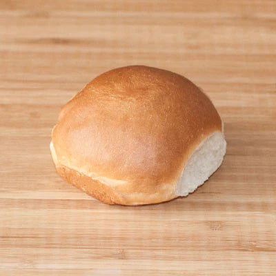 A single freshly made sliced Kaiser bun on a wooden surface.